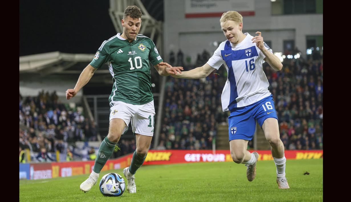 Striker Irlandia Utara, Dion Charles (kiri) berebut bola dengan bek Finlandia, Matti Peltola pada laga kualifikasi Euro 2024 Grup H di Windsor Park, Belfast, Irlandia Utara (27/3/2023). Dion Charles total mencetak dua gol bagi Irlandia Utara dalam dua laga kualifikasi Euro 2024. Dua gol tersebut dilesakkan ke gawang San Marino saat menang 2-0, sementara di laga kedua menghadapi Finlandia ia gagal menyumbang gol saat kalah 0-1. (AP Photo/Peter Morrison)