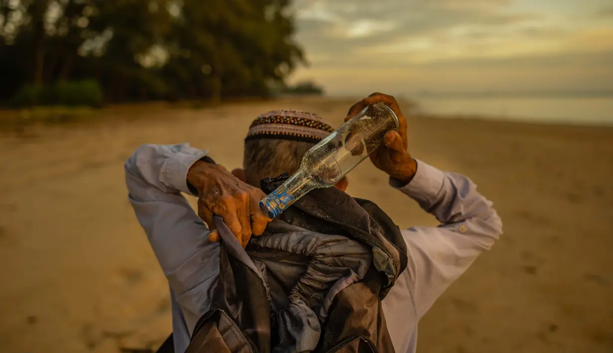 Tengku Mohamad Ali Mansor menyimpan botol kaca yang dia temukan di pantai dalam ranselnya saat matahari terbit di sebuah pantai di desa Mangkuk di distrik Setiu negara bagian Terengganu Malaysia timur pada 12 September 2020. (AFP/Mohd Rasfan)