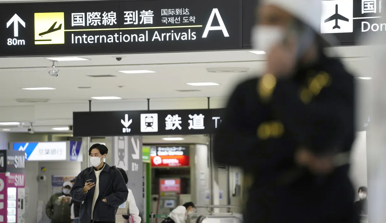 Pria memegang ponsel saat berdiri di terminal kedatangan internasional di Bandara Narita, timur Tokyo, Kamis (2/12/2021). Maskapai-maskapai internasional diminta menangguhkan reservasi baru pada semua penerbangan masuk ke Jepang hingga akhir Desember terkait varian Omicron. (AP Photo/Hiro Komae)