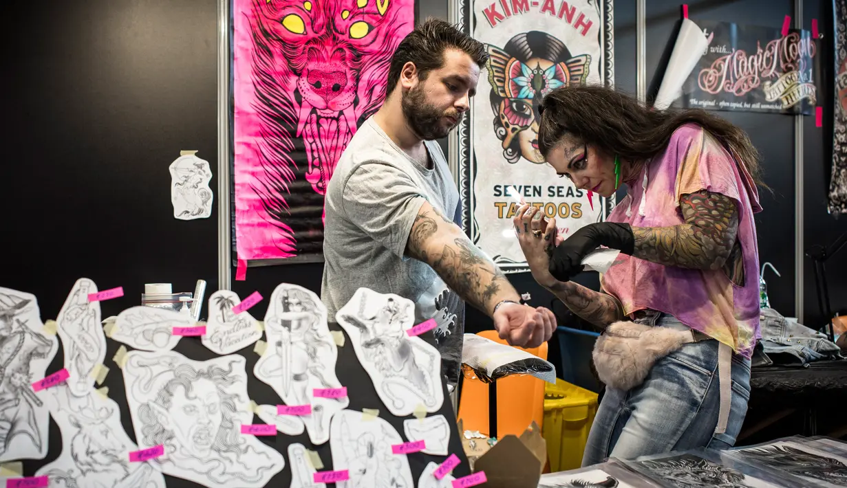 Seorang seniman tato serius menggambar di tangan pria selama acara Paris Tattoo Convention di Grand Halle de la Villette, Paris, Prancis, Jumat (9/3). Paris Tattoo Convention tahun ini merupakan yang kedelapan. (Philippe LOPEZ/AFP)