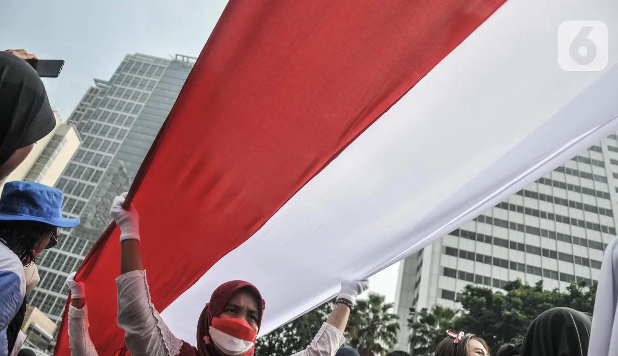 Peserta membentangkan bendera Merah Putih raksasa di kawasan Bundaran HI, Jakarta Pusat, Minggu (28/8/2022). Sebanyak 50.000 orang membentangkan bendera merah putih sepanjang 1.700 meter dari kawasan Monas hingga Bundaran HI yang merupakan rangkaian dalam memperingati Hari Kemerdekaan Indonesia dengan tema 'Pulih Lebih Cepat, Bangkit Lebih Kuat. (merdeka.com/Iqbal S Nugroho)