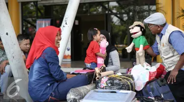Seorang pendongeng yang tergabung dalam Gerakan Para Pendongeng untuk Kemanusiaan (GePPUK) menghibur pemudik anak-anak di Pelabuhan Tanjung Priuk, Jakarta, Kamis (30/6). (Liputan6.com/Faizal Fanani)
