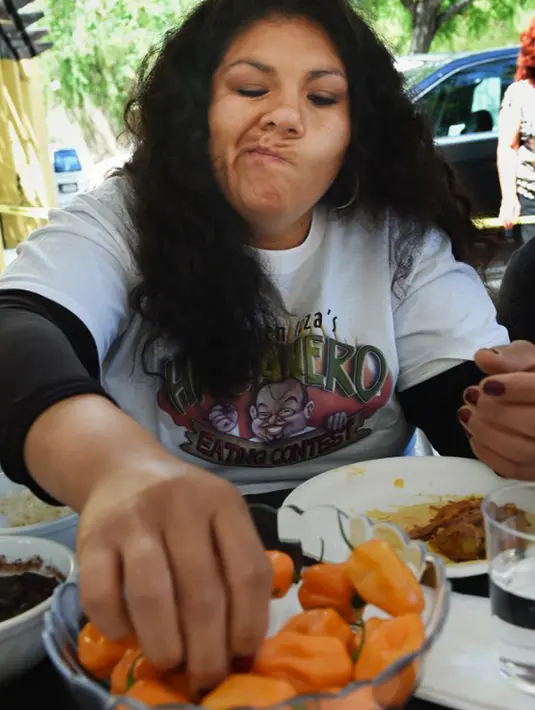 Ekpresi Teresa de Jesus Sandoval, salah satu pesetta lomba makan cabai saat menyelesaikan makan 60 cabai Habanero dalam Habanero Eating Contest di Restoran Chichen Itza, Los Angeles, Minggu (21/6). (AFP PHOTO/Mark RALSTON)
