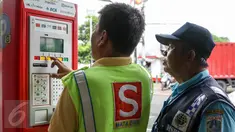 Petugas parkir melakukan transaksi dengan mesin terminal parkir elektronik (TPE) di jalan Sabang, Jakarta, Kamis (25/2). Pemprov DKI Jakarta berencana menambah mesin terminal parkir elektronik (TPE) atau parkir meter. (Liputan6.com/Yoppy Renato)