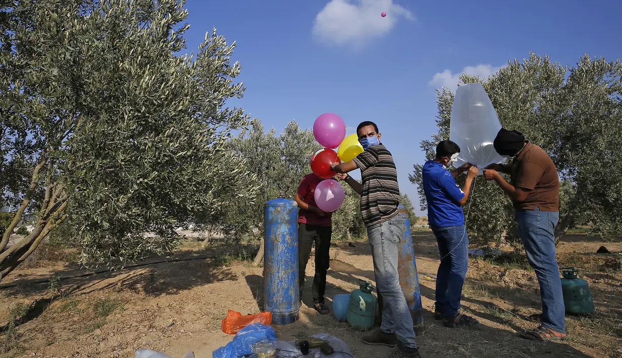 Sejumlah pria Palestina menyiapkan balon dengan alat peledak yang akan diterbangkan ke  Israel disepanjang perbatasan Israel-Jalur Gaza (12/8/2020). Serangan balon api yang dilancarkan menyebabkan terjadinya puluhan kebakaran di areal pertanian Israel. (AFP Photo/Mohammed Abed)