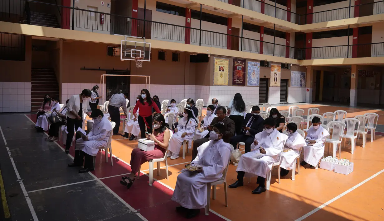 Anak-anak dan orang tua mereka, mengenakan masker pelindung, menunggu dimulainya Misa Perjamuan Kudus pertama di tengah pandemi virus corona baru di gereja Katolik Nuestra Senora de la Merced di Lima, Peru, Jumat (3/12/2021). (AP Photo/Martin Mejia)