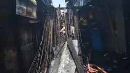 Seorang warga berusaha memotong sisa kabel listrik setelah insiden kebakaran sebuah pemukiman padat penduduk dekat pelabuhan di Manila, Filipina, Selasa (9/5). Mereka berebut mengumpulkan tembaga dari sisa kabel listrik. (TED ALJIBE/AFP)