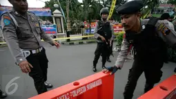 Petugas kepolisian bersiap memasang garis polisi di lokasi bom bunuh diri di Mapolresta Solo, Jawa Tengah, Selasa (5/7). Garis polisi itu dipasang mulai dari sisi barat jalan Adi Sucipto menuju sisi timur Jalan KS Tubun. (Liputan6.com/Boy Harjanto)