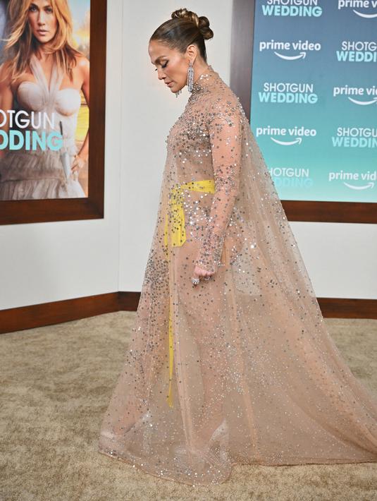 Jennifer Lopez tiba menghadiri pemutaran perdana film "Shotgun Wedding" di Los Angeles di TCL Chinese Theater di Hollywood, California (18/1/2023). Dihiasi dengan payet, roknya jatuh ke lantai dan menampilkan bodysuit cokelat yang dikenakannya di balik gaun itu, diikat dengan pita kuning cerah di pinggangnya. (Frederic J. Brown / AFP)