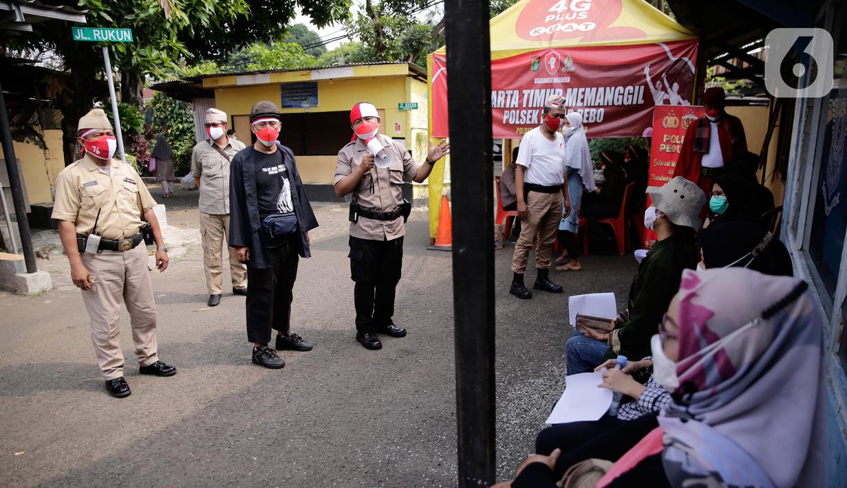 Petugas kepolisian berpakaian pejuang jaman dulu saat memberikan pengarahan kepada warga yang akan ikut vaksin Covid-19 di Polsek Pasar Rebo, Jakarta, Selasa (17/8/2021). Para petugas berkostum pejuang jaman dulu memeriahkan HUT ke-76 Republik Indonesia. (Liputan6.com/Angga Yuniar)