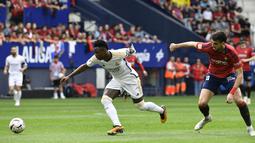 Pemain Real Madrid, Vinicius Junior, berebut bola dengan pemain Osasuna, Ruben Garcia, pada laga pekan ke-29 La Liga 2023/2024 di Stadion El Sadar, Sabtu (16/03/2024). Hasil ini membuat Real Madrid semakin perkasa di puncak klasemen sementara La Liga dengan raihan 72 angka. (AP Photo/Alvaro Barrientos)