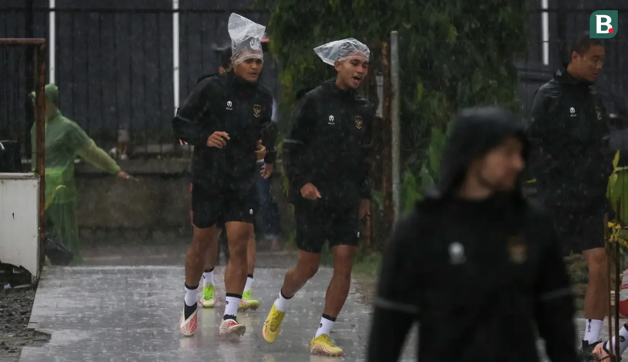Pemain Timnas Indonesia, Marselino Ferdinan (kanan) dan Rachmat Irianto berlari menembus hujan saat latihan Timnas Indonesia menjelang laga leg pertama semifinal Piala AFF 2022 menghadapi Vietnam yang berlangsung di Lapangan A, Kompleks Gelora Bung Karno, Jakarta, Rabu (04/01/2023). (Bola.com/Bagaskara Lazuardi)