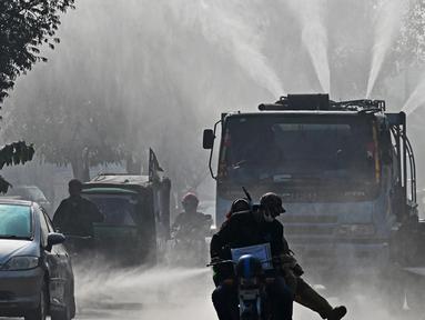 Sebuah kendaraan Badan Air dan Sanitasi (WASA) menyemprotkan air dengan menggunakan pistol anti-kabut asap untuk mengurangi polusi udara di tengah kondisi kabut asap tebal di Lahore, Pakistan pada 19 November 2024. (Arif ALI/AFP)
