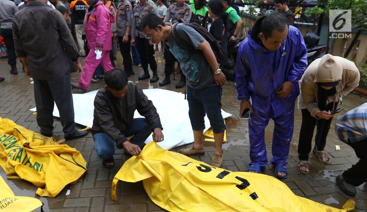 Warga melihat jenazah korban gelombang Tsunami Anyer di Puskesmas Carita, Banten, Minggu (23/12). Tim SAR masih terus melakukan pencarian jenazah yang sebagian besar berasal dari Pantai Carita. (Liputan6.com/Angga Yuniar)