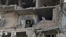 Tim penyelamat melakukan upaya pencarian korban di sebuah bangunan tempat tinggal bertingkat, yang sebagian hancur setelah serangan pesawat tak berawak pada malam hari di Kyiv pada 30 Mei 2023. (Sergei SUPINSKY/AFP)