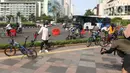 Seorang wanita berpose dengan sepedanya di kawasan Bundaran HI, Jakarta, Minggu (3/01/2021). Sejumlah aktivitas pesepeda melintasi jalan sudirman-thamrin di minggu pertama 2021, meski Car Free Day saat ini belum diberlakukan karena PSBB. (Liputan6.com/Herman Zakharia)