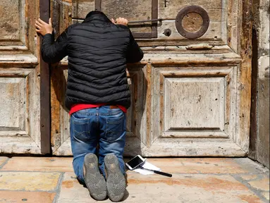 Seorang peziarah berdoa di gerbang Gereja Makam Kudus di Kota Tua Yerusalem, Minggu (25/2). Para pemimpin Kristen mengambil langkah langka untuk menutup gereja yang menjadi tempat di mana Yesus disalibkan, wafat, dimakamkan, dan bangkit. (GALI TIBBON/AFP)