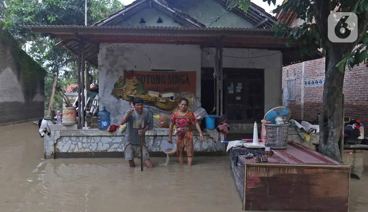 Keluarga Pak Ranin berpose di depan kediamannya Desa Sumber Urip Pebayuran, Kabupaten Bekasi, Jawa Barat, Senin (22/2/2021). Banjir merenda keluarga tersebut merapikan barang-barang dan bersihkan rumah yang sudah surut. (Liputan6.com/Herman Zakharia)