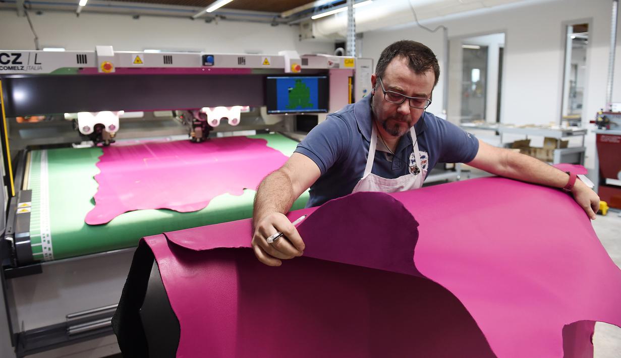 Seorang pengrajin memotong lembaran kulit saat bekerja di bengkel produsen barang-barang mewah Hermes di Allenjoie, Perancis, Kamis (5/4). Hermes didirikan oleh Thierry Hermes pada tahun 1837. (SEBASTIEN BOZON/AFP)