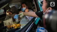 Relawan membagikan masker kepada pengemudi mobil di Bundaran HI, Jakarta, Selasa (17/3/2020). Sebanyak 3.000 masker dibagikan gratis kepada pengguna jalan sebagai bentuk keprihatinan sekaligus berpartisipasi dalam upaya mencegah penyebaran virus corona COVID-19. (Liputan6.com/Faizal Fanani)