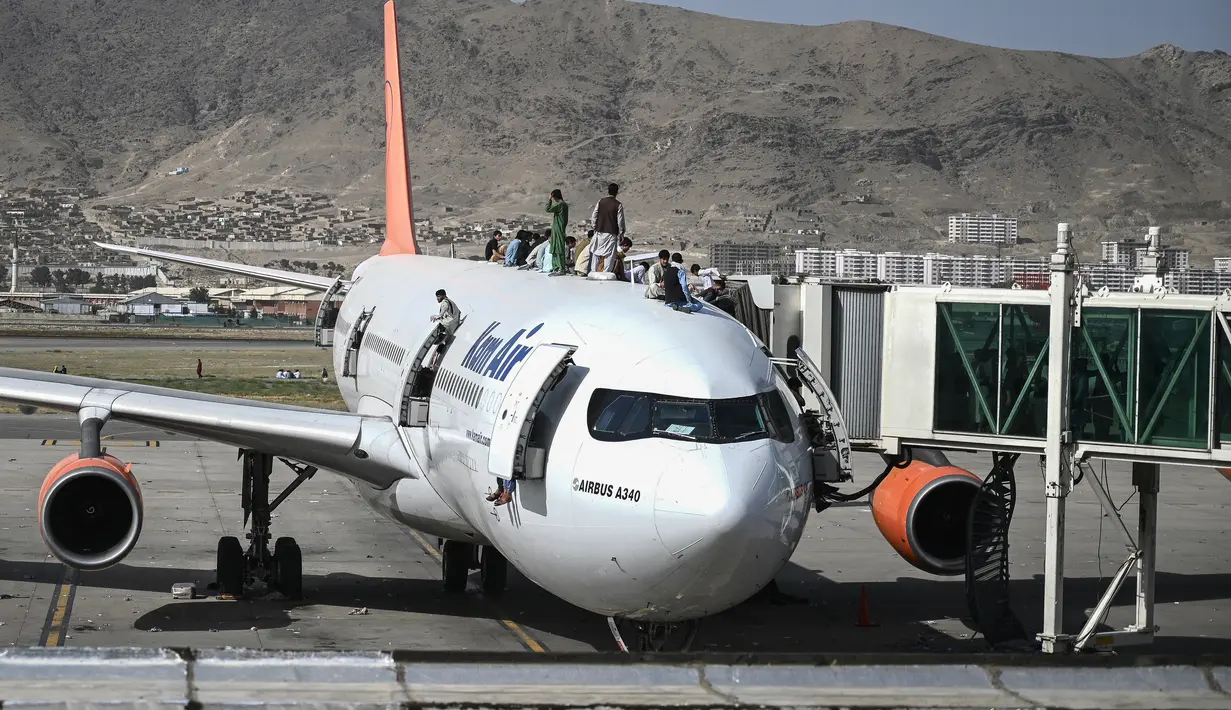 Orang-orang Afghanistan naik ke atas sebuah pesawat saat mereka menunggu di bandara Kabul (16/8/2021). Ribuan orang mencoba melarikan diri dari Taliban yang segera menguasai penuh Afghanistan. (AFP/Wakil Kohsar)