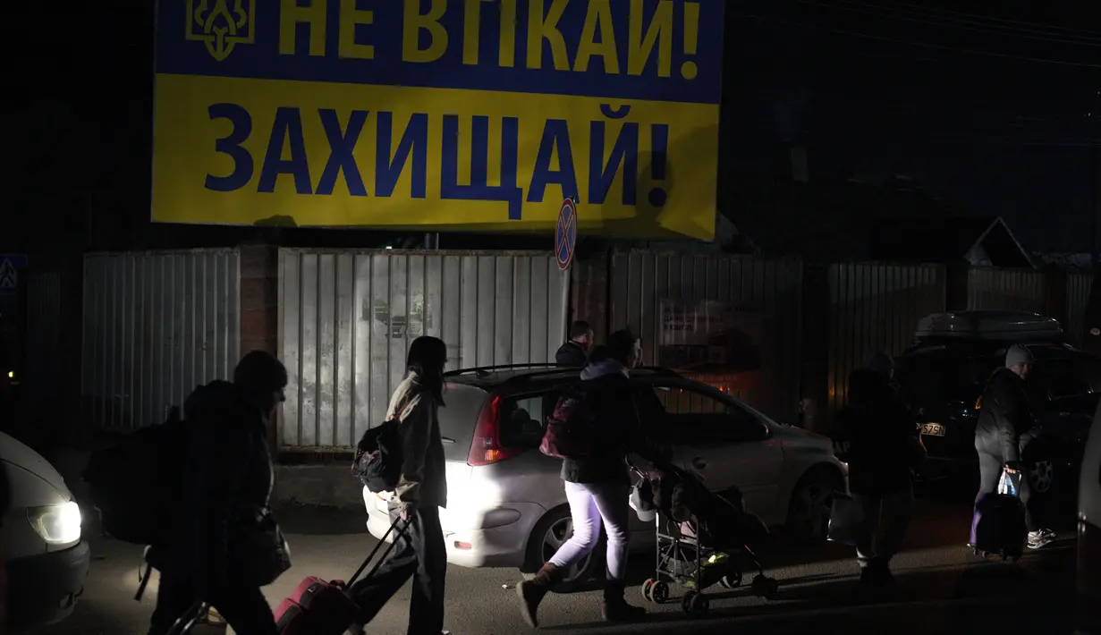 Pengungsi yang melarikan diri dari perang di Ukraina, berjalan di sepanjang jalan mendekati perbatasan dengan Polandia di Shehyni, Ukraina, Minggu (6/3/2022). Jumlah orang Ukraina yang dipaksa meninggalkan negara mereka meningkat menjadi 1,5 juta. (AP Photo/Daniel Cole)