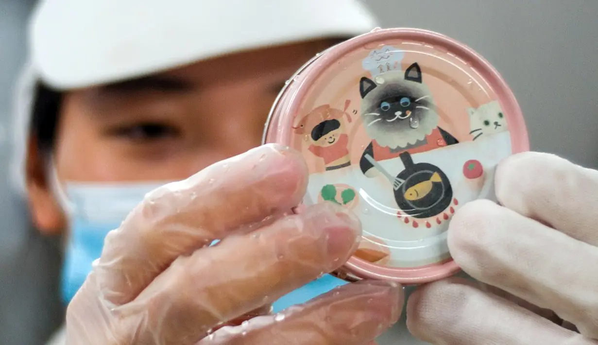 Gambar yang diambil pada 27 Oktober 2021 ini menunjukkan seorang pekerja memeriksa kaleng sampel makanan kucing yang bahan dasarnya terbuat dari kepompong ulat sutra di sebuah pabrik makanan hewan peliharaan di Miaoli, Taiwan. (Sam Yeh/AFP)