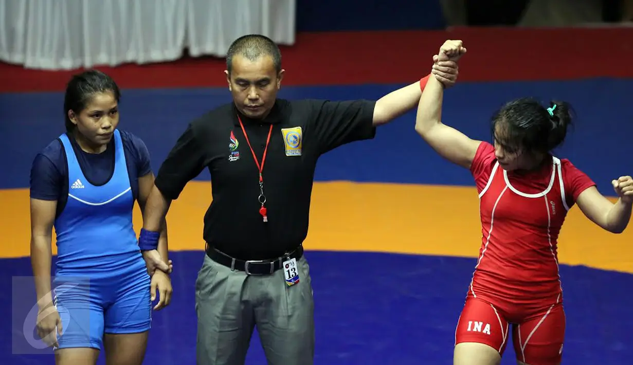 Pegulat putri Kaltim, Inadrah (kanan) mengangkat tangan usai memastikan menang melawan pegulat Sumbar Mardiatul di final gaya bebas kelas 53 kg putri pada PON XIX di Arena Saparua Sport Park, Bandung, Sabtu (24/9). (Liputan6.com/Helmi Fithriansyah)