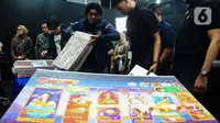 Petugas merapikan barang bukti usai sejumlah Menteri Kabinet Merah Putih memberikan keterangan terkait capaian desk pemberantasan perjudian daring dan desk keamanan siber dan perlindungan data di Kantor Kementerian Komunikasi dan Digital (Komdigi), Jakarta, Kamis (21/11/2024). (Liputan6.com/Angga Yuniar)