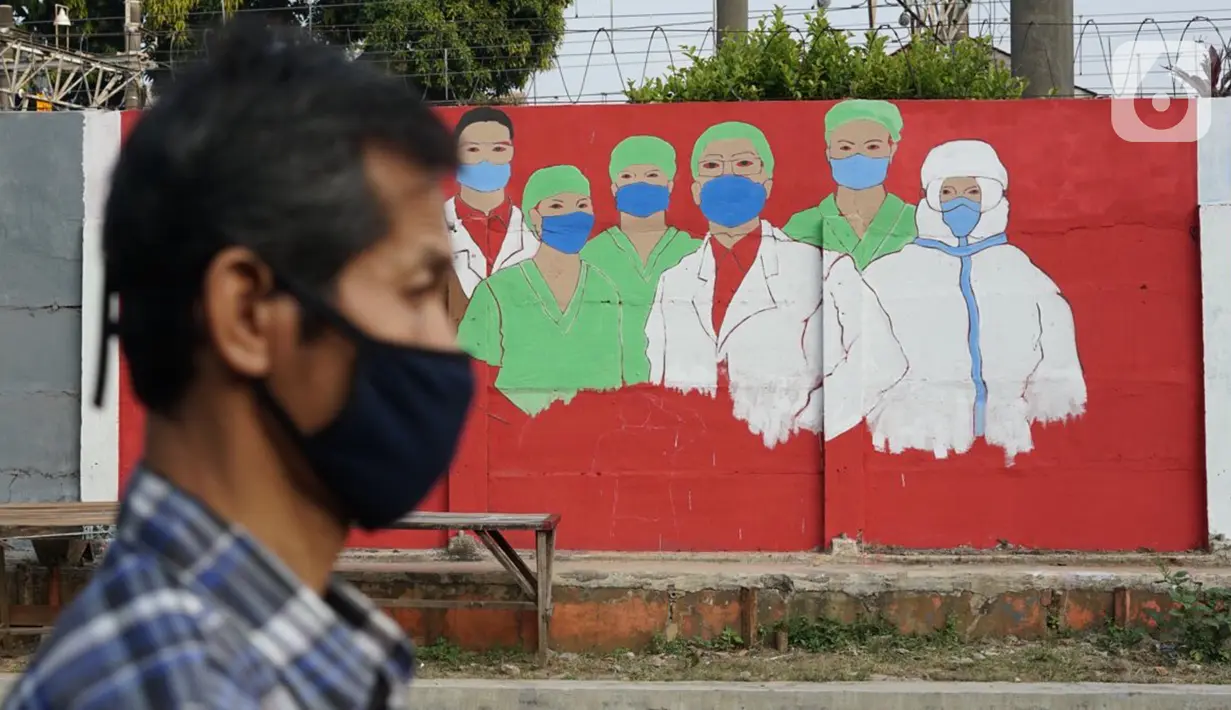 Warga melintas di depan mural bertema covid-19 di Bukit Duri, Jakarta, Minggu (30/8/2020). Mural yang dibuat petugas PPSU bertujuan untuk mengingatkan masyarakat akan bahaya covid-19, sehubungan dengan masih tingginya jumlah kasus positif covid-19 di Jakarta. (Liputan6.com/Immanuel Antonius)