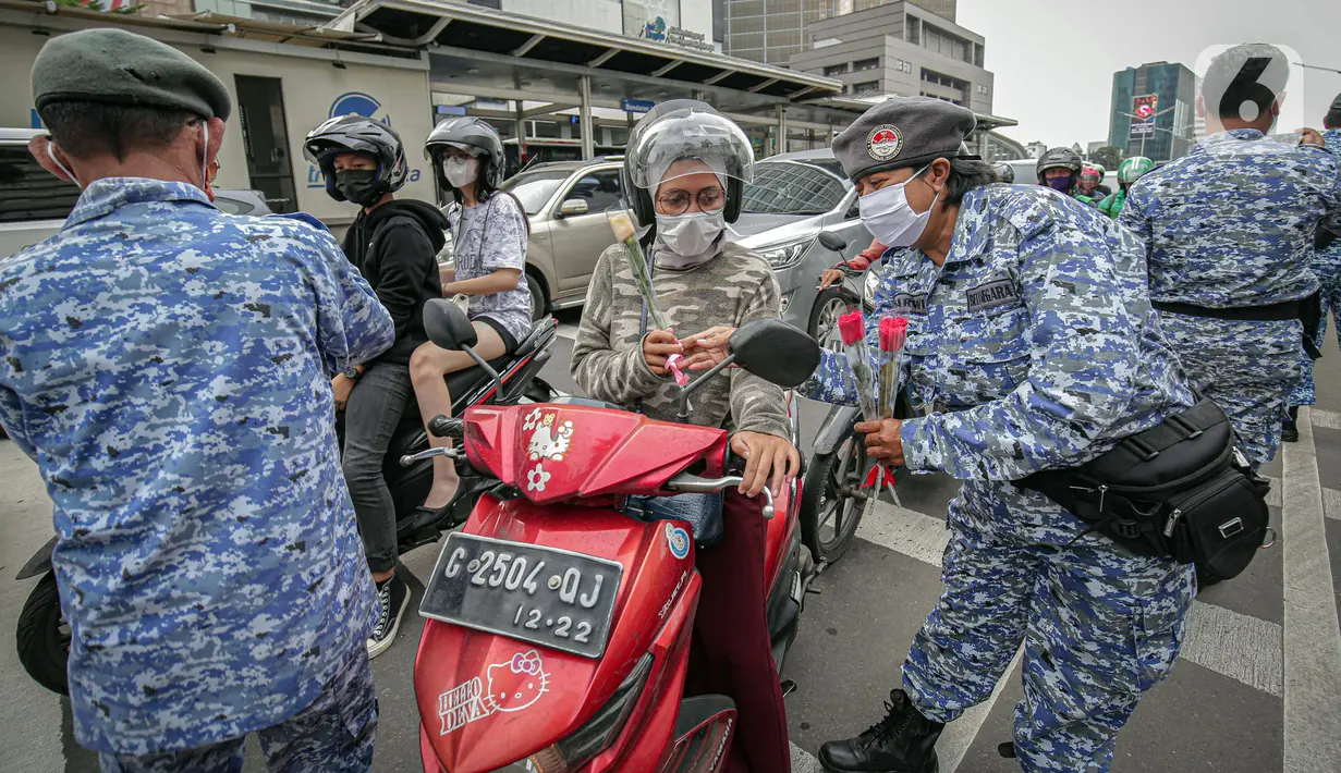 Sejumlah perserta yang tergabung dalam Forum Kader Bela Negara DKI Jakarta membagikan bunga dan masker kepada pengguna jalan di Jalan Thamrin, Jakarta, Rabu (22/12/2021). Aksi tersebut merupakan bentuk apresiasi terhadap kaum perempuan terutama pada peringatan Hari Ibu. (Liputan6.com/Faizal Fanani)