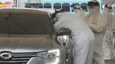 Petugas medis dengan pakaian pelindung mengambil sampel dari pengemudi di layanan "drive-thru" di Goyang, 1 Maret 2020. Untuk mengefisiensi waktu, pemerintah Korea Selatan membuat layanan tes uji virus corona COVID-19 kepada warganya via drive thru (tanpa turun). (AP/Ahn Young-joon)