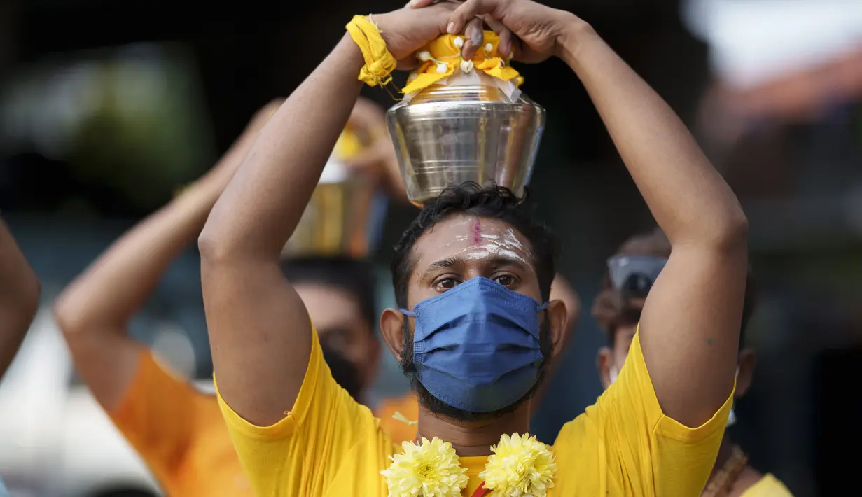 Umat Hindu mengenakan masker membawa teko susu dalam prosesi selama festival Thaipusam sebagai umat mematuhi prosedur operasi standar yang ketat karena pandemi COVID-19 di Gua Batu di pinggiran Kuala Lumpur, Malaysia, Selasa (18/1/2022). (AP Photo/ Vincent Thian)
