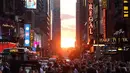 Orang-orang mengambil gambar matahari terbenam di antara pencakar langit ketika fenomena Manhattanhenge di 42nd street di Times Square, New York City, Kamis (12/7). Manhattanhenge dimana saat matahari terbenam sejajar dengan jalan. (AFP/TIMOTHY A. CLARY)