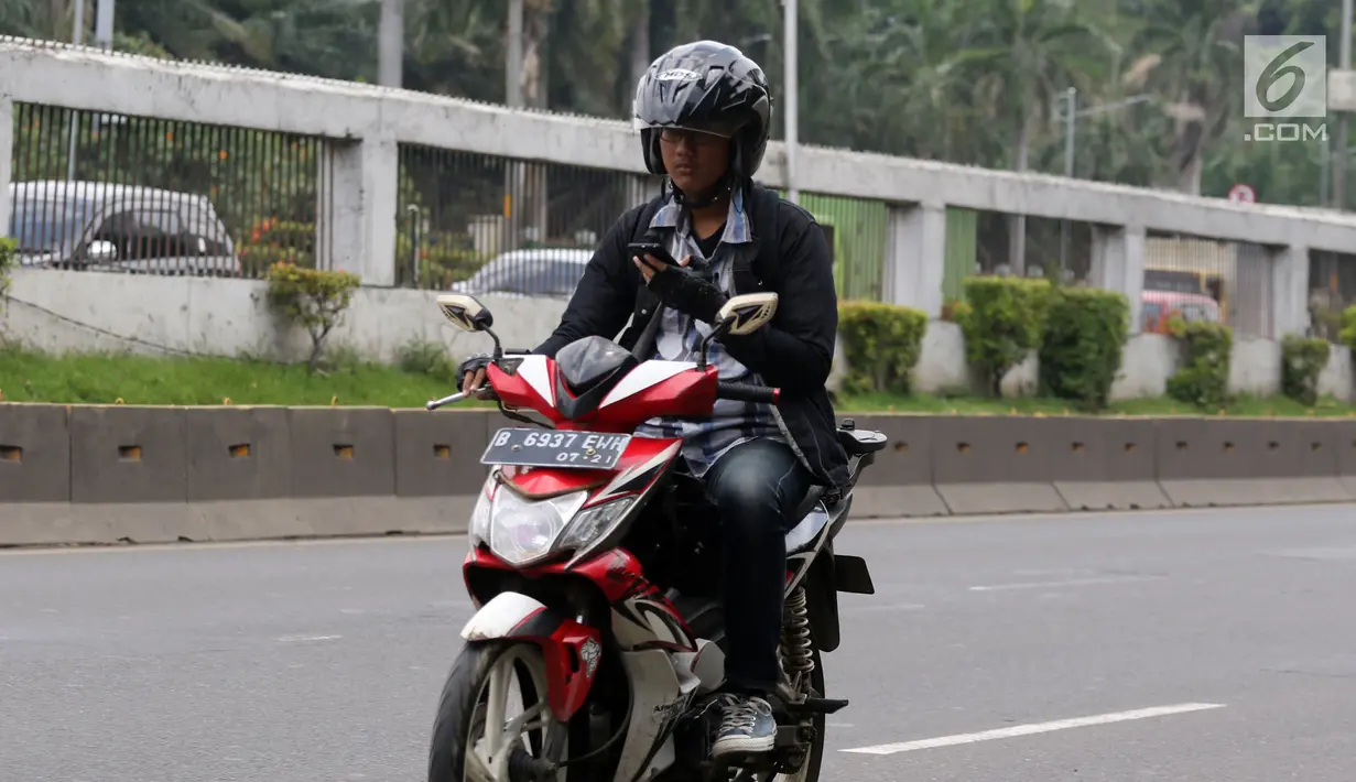 Pengendara mengoperasikan telepon seluler sambil mengendarai sepeda motor di Jalan Gatot Subroto, Jakarta, Kamis (8/3). Mengoperasikan telepon seluler sambil mengendarai akan diancam denda Rp 750 ribu (pasal 283 UU no 22/2009).(Liputan6.com/Arya Manggala)