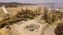 Properti yang terbakar terlihat di atas Danau Oroville yang surut di Oroville, California, Amerika Serikat, 5 September 2021. Danau Oroville saat ini hanya memiliki kapasitas air sebanyak 23 persen dan mengalami kekeringan ekstrem. (JOSH EDELSON/AFP)