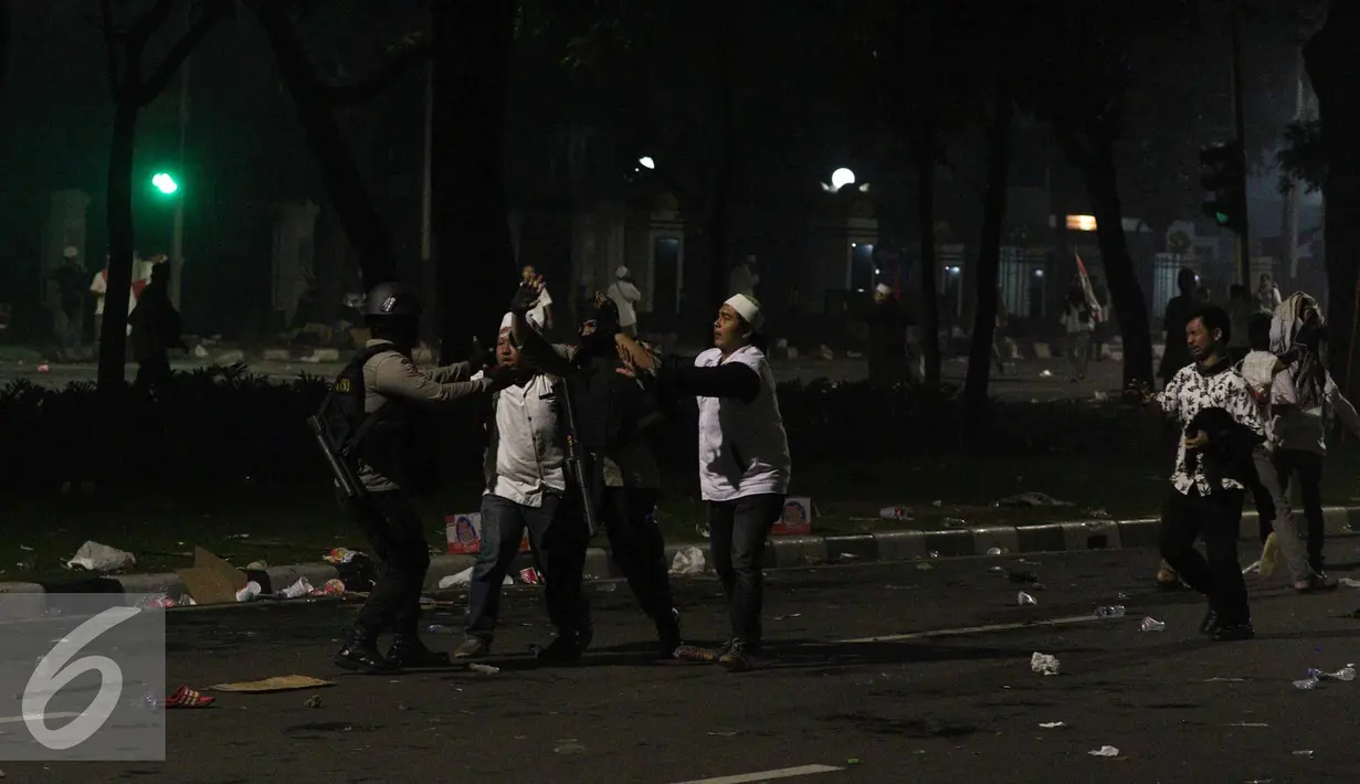 Pendemo dan polisi saling melindungi saat bentrok terjadi di jalan Medan Merdeka Barat, Jakarta, Jumat (4/11). (Liputan6.com/Faizal Fanani)
