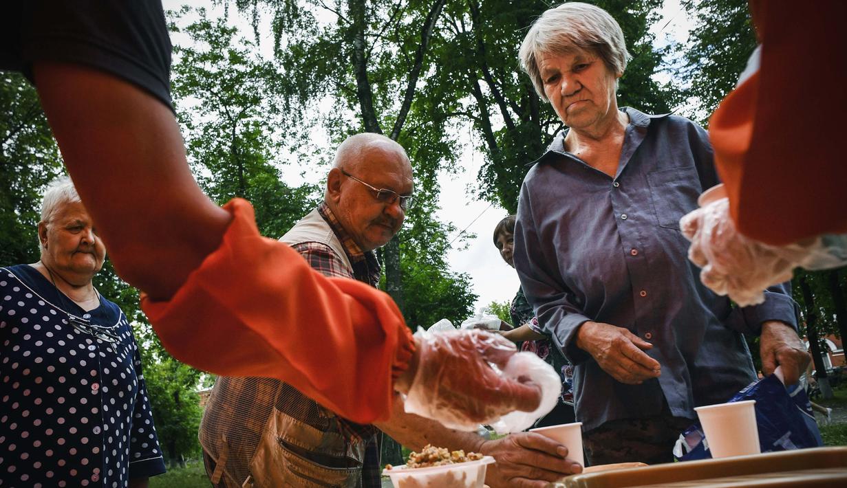 Zinaida Ibragimova (69) menerima santunan amal di asrama pekerja pabrik tekstil Proletarka di Kota Tver, Rusia, 8 Agustus 2020. Proletarka merupakan satu set barak unik yang terdiri dari sekitar 50 bangunan neo-Gotik. (Alexander NEMENOV/AFP)