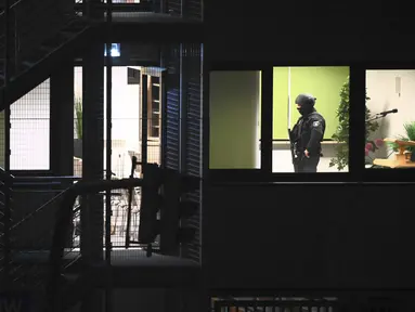 Petugas polisi dengan peralatan khusus berjalan melalui gedung yang digunakan gereja Saksi-Saksi Yehuwa di Hamburg, Jerman, Kamis (9/3/2023). Sejumlah orang pun dilaporkan tewas dalam penembakan membabi buta tersebut. (Jonas Walzberg/dpa via AP)