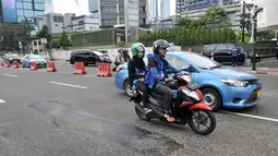 Kendaraan melintas di dekat jalan berlubang di Jalan Jenderal Sudirman, Jakarta, Senin (11/3). Jalanan di pusat kota tersebut berlubang dapat membahayakan keselamatan pengendara yang melintas. (merdeka.com/Iqbal S. Nugroho)