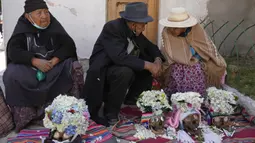 Orang-orang duduk dengan tengkorak manusia yang dihias untuk diberkati oleh seorang imam selama Festival Natitas di Pemakaman Umum di La Paz, Bolivia, Selasa (8/11/2022). Tradisi tahunan ini merayakan kematian di Bolivia dengan tengkorak yang dirawat dan didekorasi oleh mereka yang menggunakannya sebagai jimat untuk perlindungan. (AP Photo/Juan Karita)