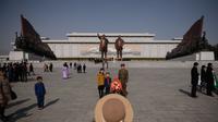 Sebuah keluarga berfoto di Mansu Hill dengan latar patung Kim Il-sung dan Kim Jong-il (AFP)