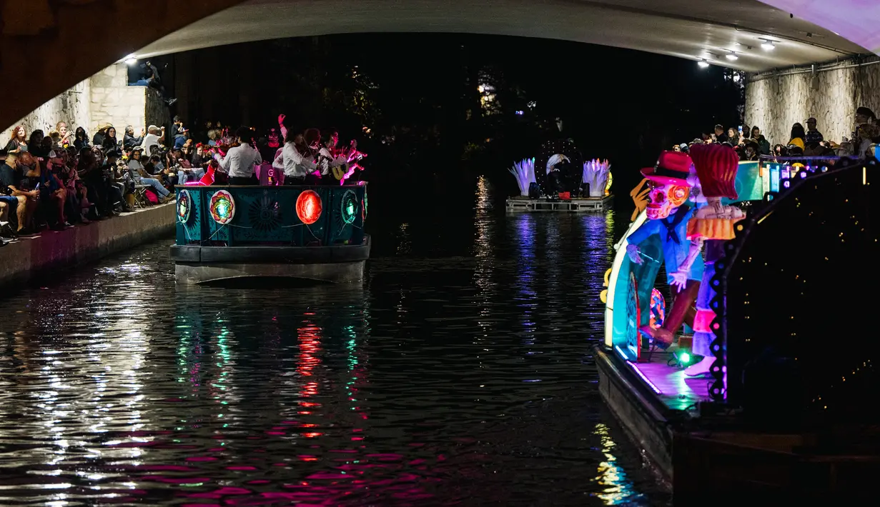 Kendaraan hias melintasi bawah jembatan selama parade Hari Sungai Mati di San Antonio, Texas, Amerika Serikat, 29 Oktober 2021. Warga berkumpul untuk merayakan, memperingati, dan mengenang orang-orang terkasih yang telah meninggal untuk Día de los Muertos tahun ini. (Brandon Bell/Getty Images/AFP)