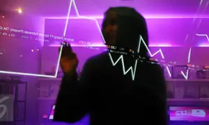 Pengunjung tengah melintasi layar pergerakan saham di BEI, Jakarta, Senin (13/2). Pembukaan perdagangan bursa hari ini, Indeks Harga Saham Gabungan (IHSG) tercatat menguat 0,57% atau 30,45 poin ke level 5.402,44. (Liputan6.com/Angga Yuniar)