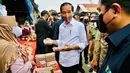 Presiden Joko Widodo (Jokowi) didampingi Menteri BUMN Erick Thohir membagikan bantuan langsung tunai (BLT) kepada para pedagang di Pasar Baru Tanjung Enim, Kabupaten Muara Enim, Sumatra Selatan, Senin (24/1/2022). Bantuan yang diberikan sebesar Rp1,2 juta per orang. (Dok. Biro Pers Kepresidenan)