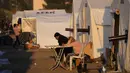 Orang-orang yang kehilangan rumah akibat gempa dahsyat, duduk di luar tenda mereka di kamp darurat, di kota Iskenderun, Turki selatan, Selasa, 14 Februari 2023. Mereka berada di tenda-tenda yang penuh sesak atau berbaris di jalan-jalan untuk menikmati makanan hangat saat pencarian korban selamat yang putus asa memasuki jam-jam terakhir. (AP Photo/Hussein Malla)