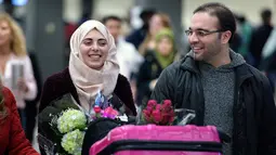 Warga Suriah berjalan bersama istrinya, sekembalinya dari Doha, tiba di Bandara Dulles, Washington, Senin (6/2). Pada Januari, mereka sempat tertahan tidak dapat masuk ke Washington akibat kebijakan imigrasi Donald Trump. (Brendan Smialowski/AFP)