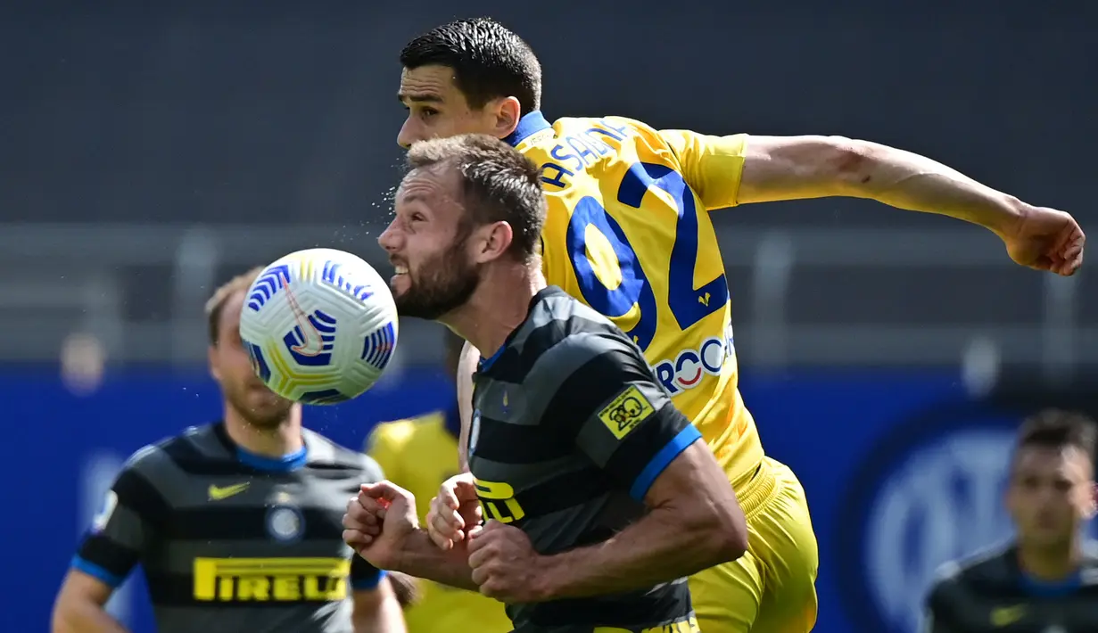 Bek Inter Milan, Stefan de Vrij (kiri) berebut bola dengan striker Hellas Verona, Kevin Lasagna dalam laga lanjutan Liga Italia 2020/2021 pekan ke-33 di San Siro Stadium, Milan, Minggu (25/4/2021). Inter menang 1-0 atas Verona. (AFP/Miguel Medina)