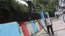 Pejalan kaki melintasi trotoar yang terhalang instalasi kabel di Jalan Kyai Maja, Jakarta, Rabu (10/4). Selain menganggu kenyamanan pejalan kaki, kondisi instalasi kabel yang semrawut tersebut juga berbahaya apabila mengandung aliran listrik. (Liputan6.com/Immanuel Antonius)