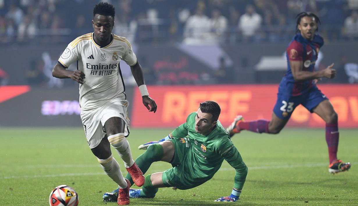 Pemain Real Madrid, Vinicius Junior (kiri) melewati kiper Barcelona, Inaki Pena Sotorres untuk mencetak gol pertama timnya pada laga final Piala Super Spanyol di Stadion King Saud University, Riyadh, Arab Saudi Senin (15/1/2024) dini hari WIB. (AP Photo)